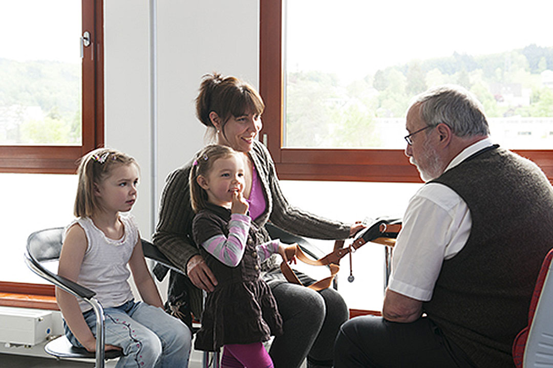 Arzt in Praxis berät Mutter mit zwei Kindern